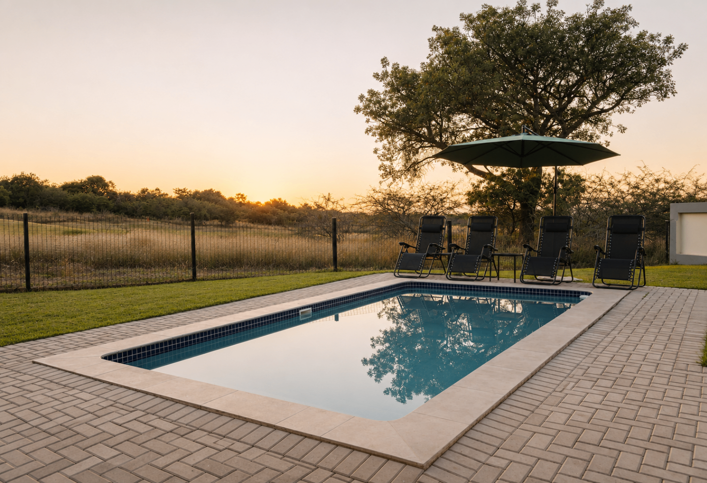 Private pool with loungers and umbrella at sunset